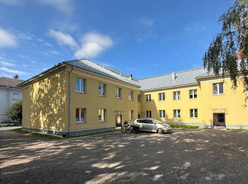 un bâtiment jaune avec une voiture garée devant lui dans l'établissement Apartment in City Center, à Tartu