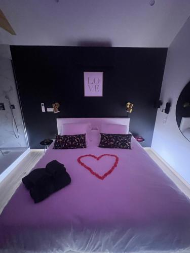 a bedroom with a purple bed with a heart on it at Suite romantique avec Spa et filet suspendu in Auteuil