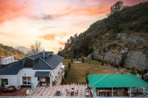 a building with a green roof next to a mountain at A Luxurious Mountain Bungalow with stunning views in Dhanaulti