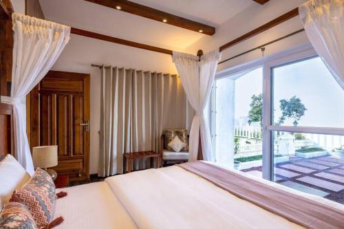 a bedroom with a bed and a large window at A Luxurious Mountain Bungalow with stunning views in Dhanaulti