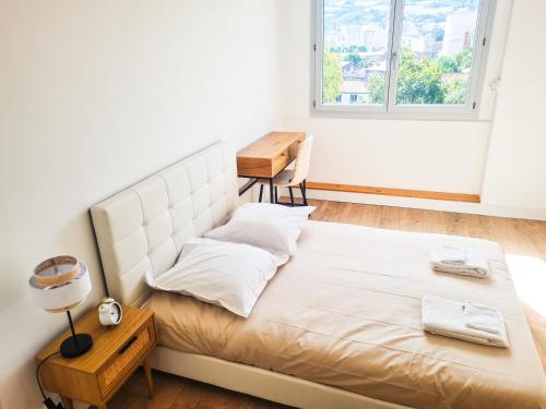 a bedroom with a large white bed with a window at Style et Confort ! T4 - Parking - Vue - Lumineux in Saint-Étienne