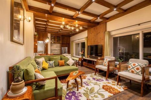 a living room with a green couch and chairs at A Luxurious Mountain Bungalow with stunning views in Dhanaulti