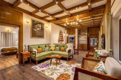 a living room with a green couch and a table at A Luxurious Mountain Bungalow with stunning views in Dhanaulti