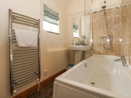 uma casa de banho com uma banheira, um chuveiro e um lavatório. em Fenns Barn em Leek