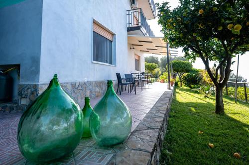 three green glass vases sitting on a stone patio at La casa del Maestro in Pisciotta