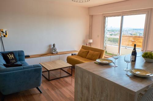 ein Wohnzimmer mit einem Tisch und einem blauen Stuhl in der Unterkunft Appartement cosy proche Paris et Stade de France in Saint-Denis