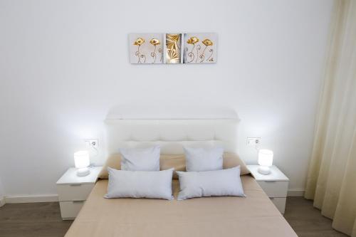 um quarto com uma cama com duas mesas brancas e duas lâmpadas em New Pineda 7 Planet Costa Dorada em La Pineda
