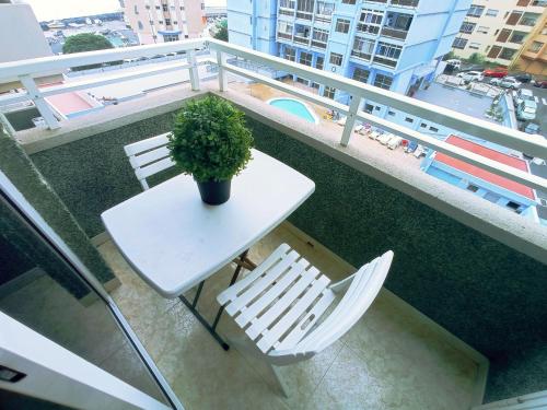 uma mesa branca e cadeiras numa varanda com uma planta em Live Candelaria Alsaca con Balcón y Vista al Mar em Candelaria