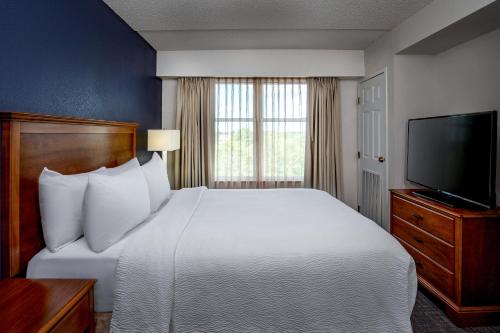 a hotel room with a bed and a flat screen tv at Residence Inn by Marriott Chesapeake Greenbrier in Chesapeake