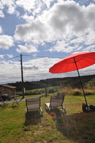 two chairs and a red umbrella in the grass at Creusoé in Saint-Marc-à-Frongier