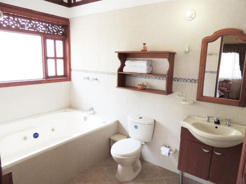 y baño con bañera, aseo y lavamanos. en Hotel Villa Cristina, en Villa de Leyva