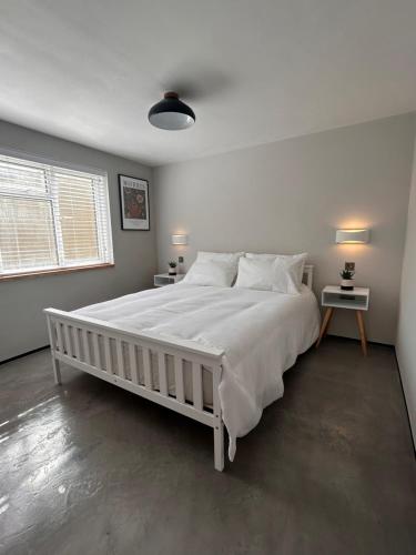 um quarto com uma grande cama branca e duas mesas em Modern Apartment Central Woodstock with Parking em Woodstock