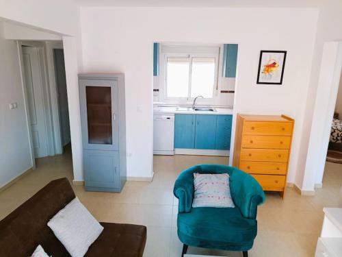 sala de estar con silla verde y cocina en Adosado cerca de la playa, en Gran Alacant