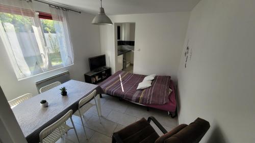 Cette petite chambre comprend une table et un lit. dans l'établissement La maison dans le jardin, à Viry-Châtillon
