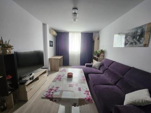 a living room with a purple couch and a tv at Modern apartment. Best location in Sofia