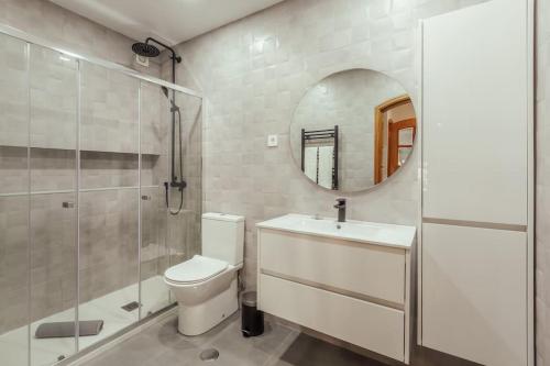 a bathroom with a toilet and a shower and a mirror at Glam 2 bedroom In Massamá in Massamá