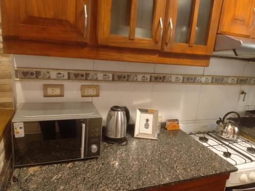 a kitchen counter with a microwave and a stove at Duplex Dorrego- Guaymallén in Guaymallen