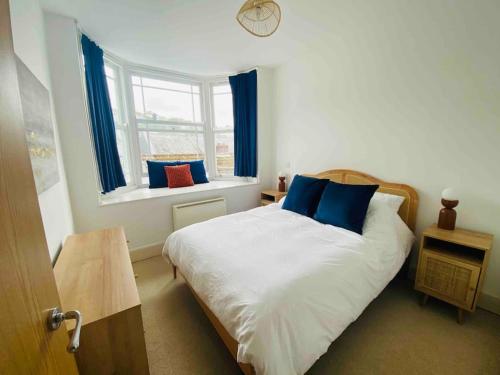 Un dormitorio con una cama con almohadas azules y una ventana en The Salt Box en Dartmouth