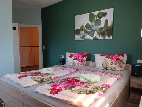 a large bed with pink flowers on top of it at Pension Thüringer Wald in Reichmannsdorf