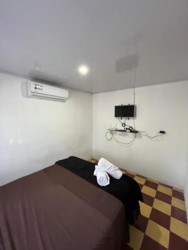 a bedroom with a bed with a black blanket and a tv at Estudio Mar Azul in Puntarenas