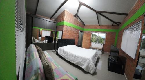 a bedroom with a white bed and a green wall at Finca Hotel el Vergel Filandia Quindio in Filandia