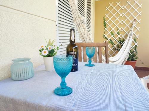 uma mesa com uma garrafa de vinho e dois copos azuis em Refugio Madeira no Caniço
