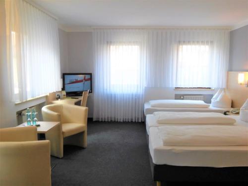a hotel room with three beds and a television at Hotel Brehm in Würzburg