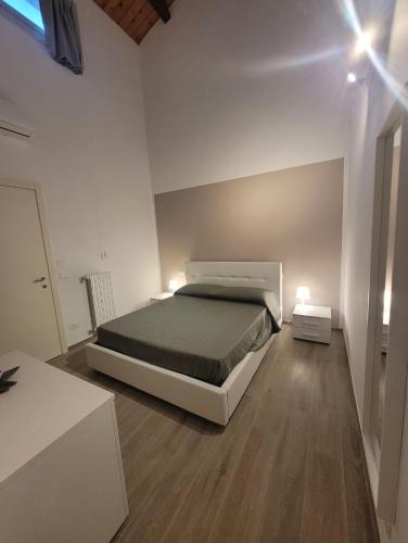 1 dormitorio blanco con 1 cama y suelo de madera en Nonna Mimma's House, en Scicli