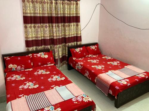 a bedroom with two beds with red covers and a curtain at Hotel Surma Residential in Dhaka