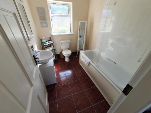 een badkamer met een toilet, een bad en een wastafel bij Quiet 2-Bedroom Buncrana Home in Buncrana