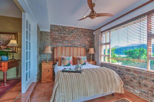 sypialnia z łóżkiem i ceglaną ścianą w obiekcie Red Door Cottage w mieście Wilderness