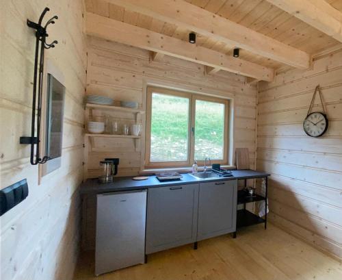 a kitchen in a log cabin with a sink and a clock at Babiogórskie klimaty in Zawoja