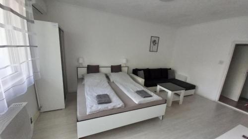 a white bedroom with a bed and a chair at Grey Harmony Apartman in Debrecen