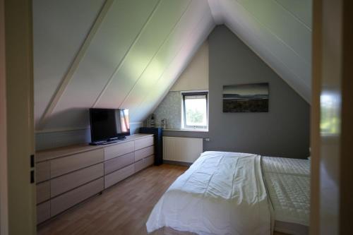a attic bedroom with a bed and a tv at Kustverhuur, Park Schoneveld, Stern 254 in Breskens