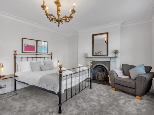 a bedroom with a bed and a chair and a fireplace at Pass the Keys Luxury Townhouse In The City in Canterbury