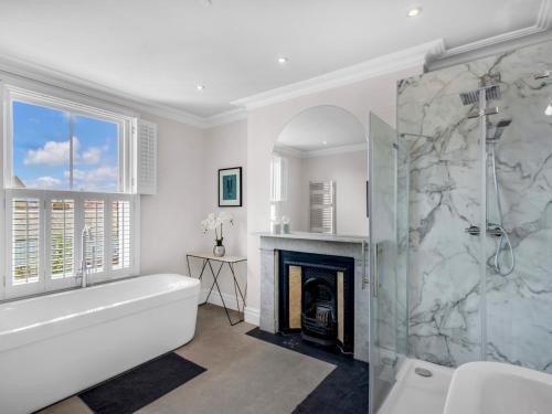 a bathroom with a bath tub and a fireplace at Pass the Keys Luxury Townhouse In The City in Canterbury