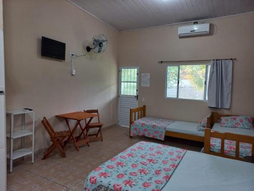 a room with two beds and a table and a window at Locação p final de semana Mourada Térrea in Caraguatatuba