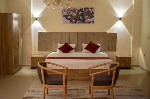 a bedroom with a large bed with two chairs at Twilight Hotel Petra in Wadi Musa
