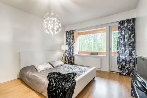a bedroom with a bed and a window and a chandelier at Upea 2 makuuhuoneen huoneisto lähellä lentokenttää! in Vantaa