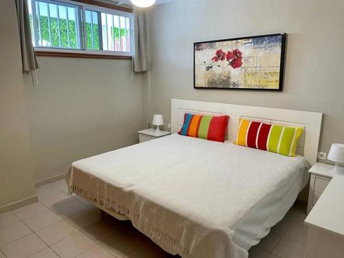 聖地亞哥港的住宿－TAGARA - 2 pools, ocean view, Puerto de Santiago，一间卧室配有一张带两个色彩缤纷的枕头的床