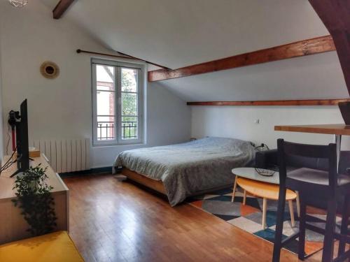 une chambre avec un lit, un bureau et une table dans l'établissement Cœur de ville avec parking+gare à proximité de Disney et Paris, à Lagny-sur-Marne