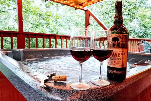 zwei Gläser Wein auf dem Tisch mit einer Flasche Wein in der Unterkunft Four Private Suites - Hot Tub - Arcade - Fast Wi-Fi - One Minute To Parkway Fun in Pigeon Forge