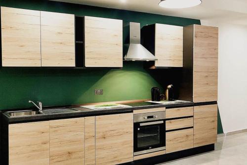 a kitchen with wooden cabinets and a green wall at BRAND NEW holiday accommodation in Xewkija
