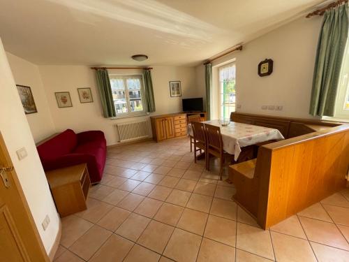 a living room with a table and a red couch at Casa Cesarina by AMA Val di Fassa in Canazei