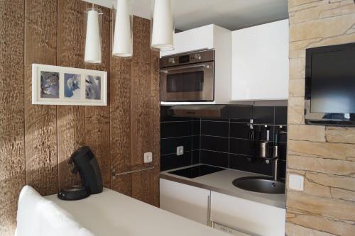 une cuisine avec des armoires blanches et un évier dans l'établissement Ski aux pieds Les 3 Vallées, aux Menuires