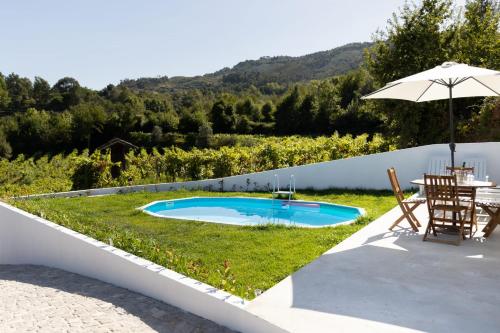 um quintal com uma piscina, uma mesa e um guarda-sol em Refugio das Vinhas em Celorico de Basto