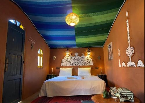 1 dormitorio con 1 cama con techo colorido en Billion Stars Desert Camp, en Mhamid