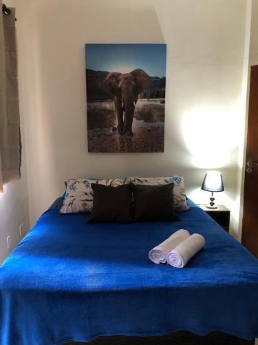 Una cama azul con dos toallas y una pintura de elefante. en Carioca en Río de Janeiro
