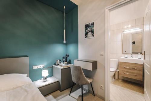 a bedroom with a bed and a desk and a sink at Apartmanház Soho in Győr