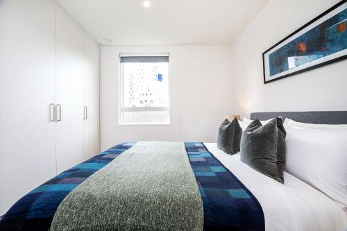 a bedroom with a bed with a blue and white comforter at Modern, Stylish, Canalside PENTHOUSE Apartment Next to Wembley Stadium! in London